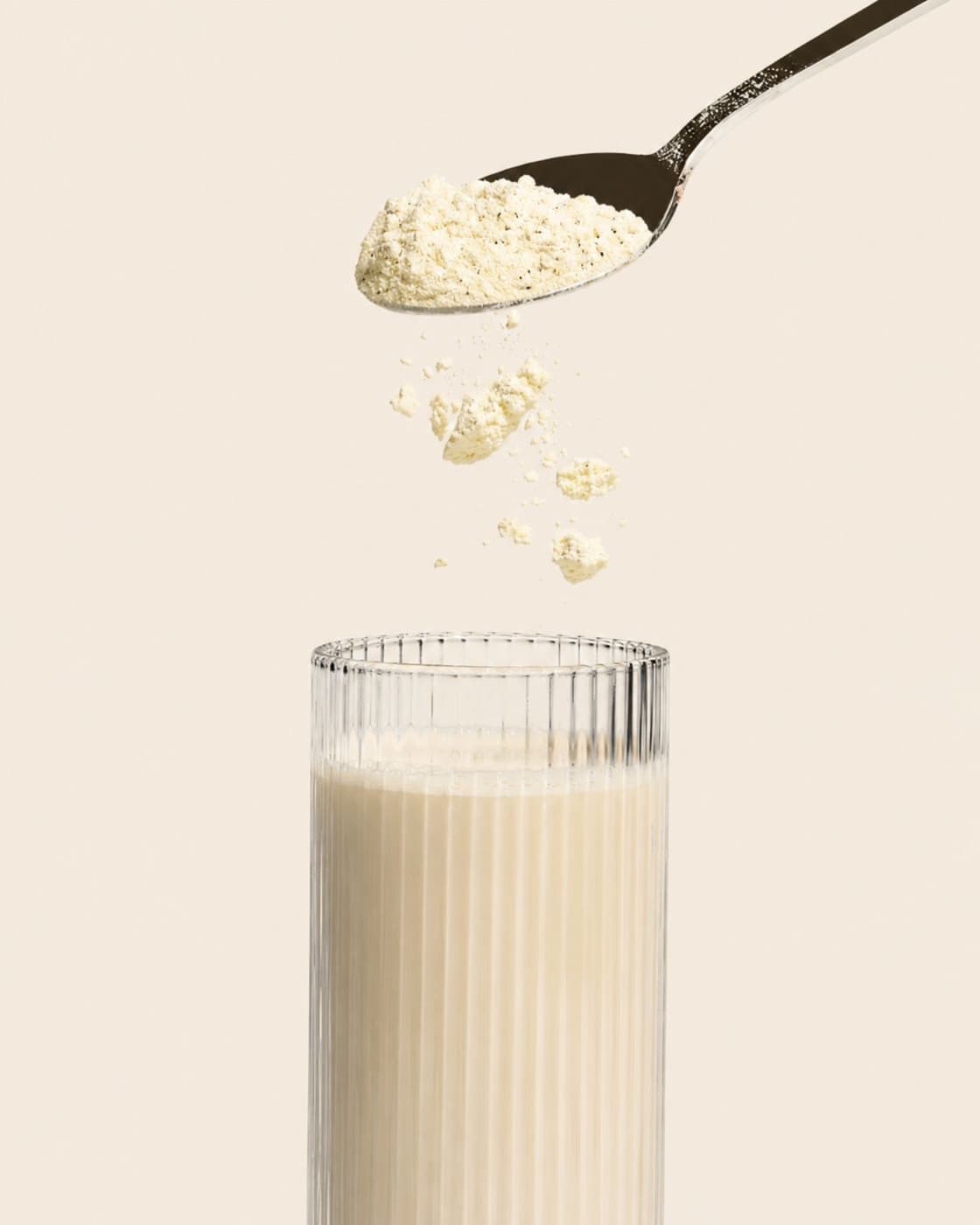 Proteinpulver fällt in ein Glas mit Milchalternative
